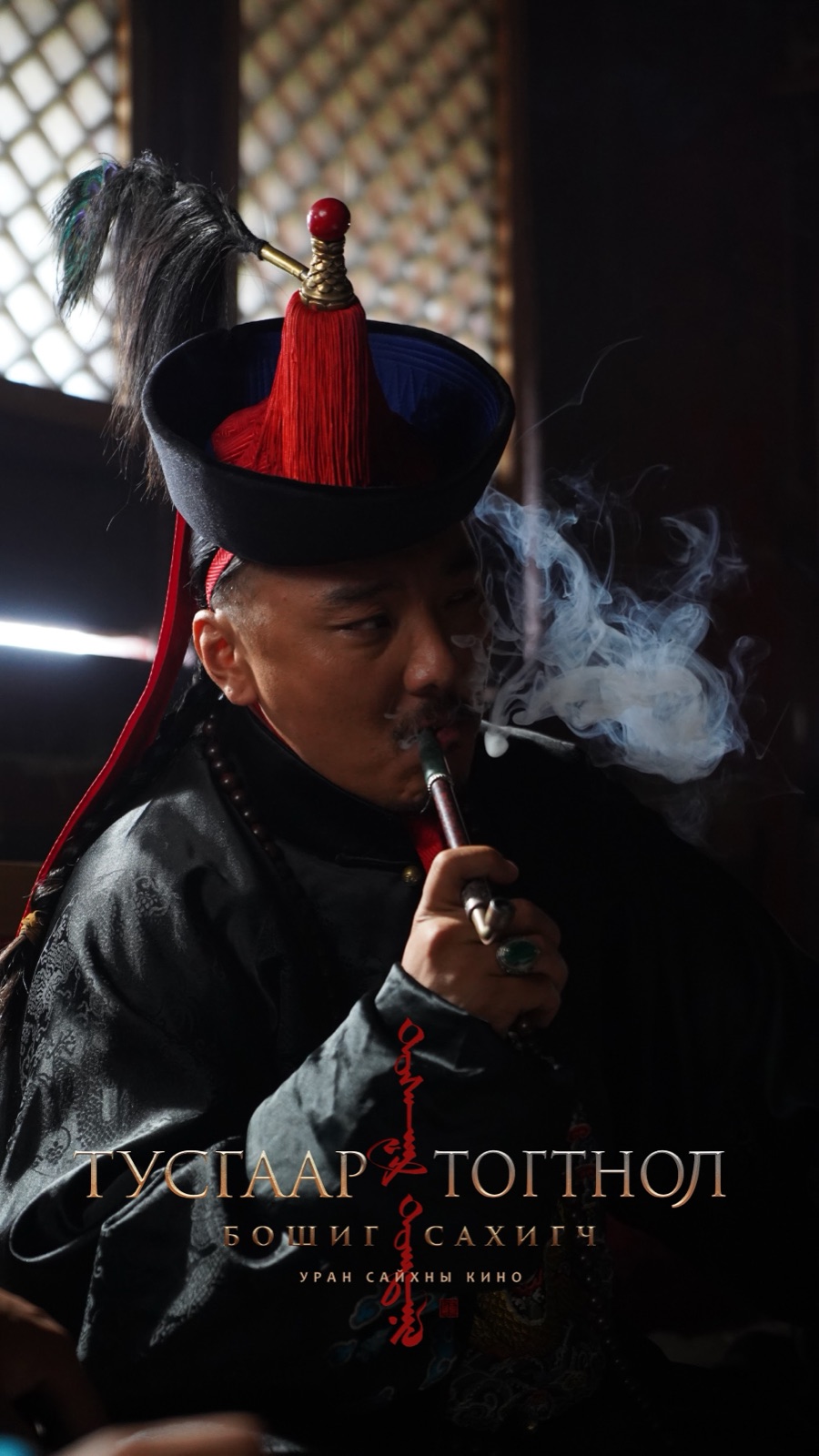 A man in a tall red-tasselled hat smoking a long pipe
